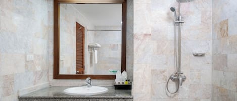 Un baño con lavamanos de encimera de granito, un espejo y una ducha con cabezal de ducha de mano.