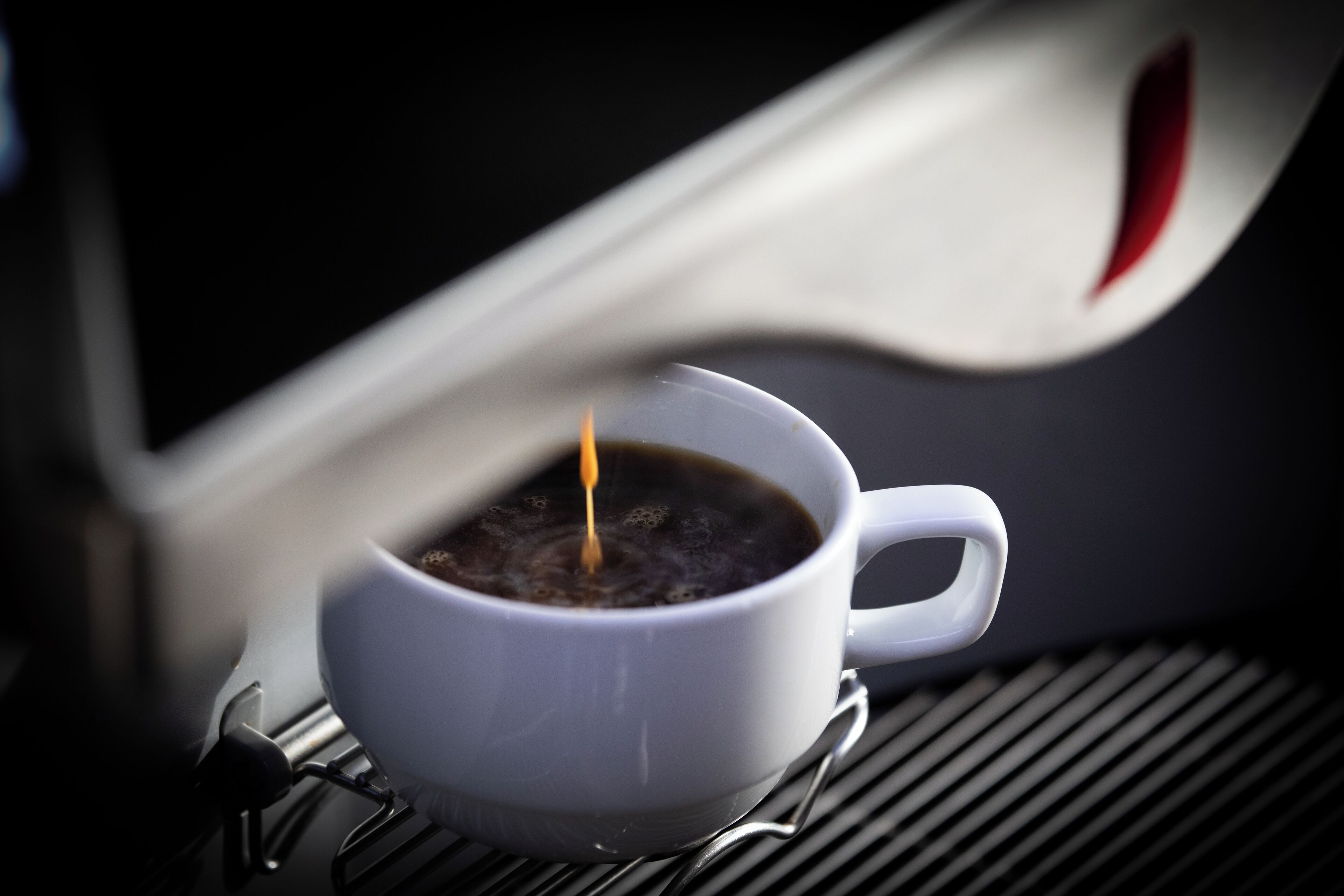 Una taza de café blanco sobre un posavasos metálico.