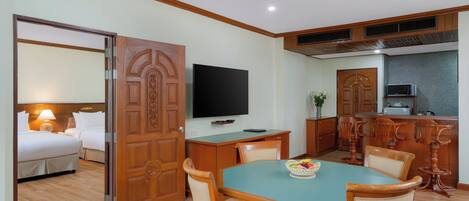 Habitación de hotel con comedor, televisor y kitchenette.
