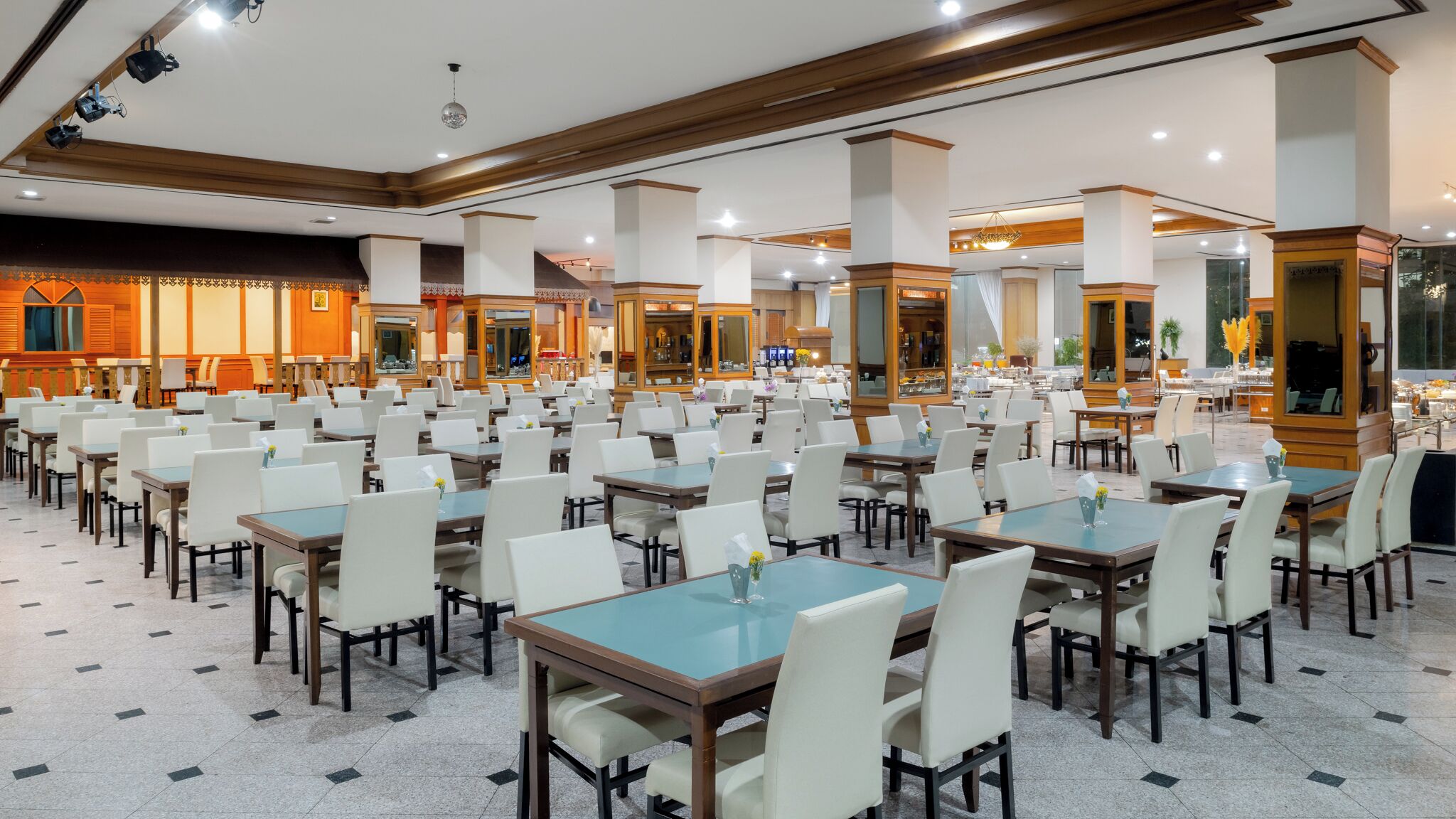 Een ruime eetruimte met meerdere tafels en stoelen, een bar en uitzicht op de stad.