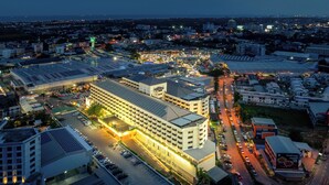 A large hotel with multiple floors, a parking lot, and a view of the surrounding cityscape. - Star Convention Hotel (Rayong)