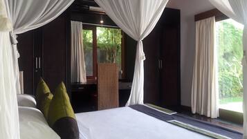 Quarto com cama, cortinas brancas e vista para o verde lá fora.