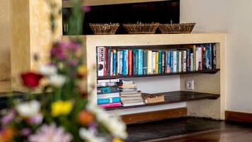Una estantería llena de libros, suelo de madera y una cesta en el estante.