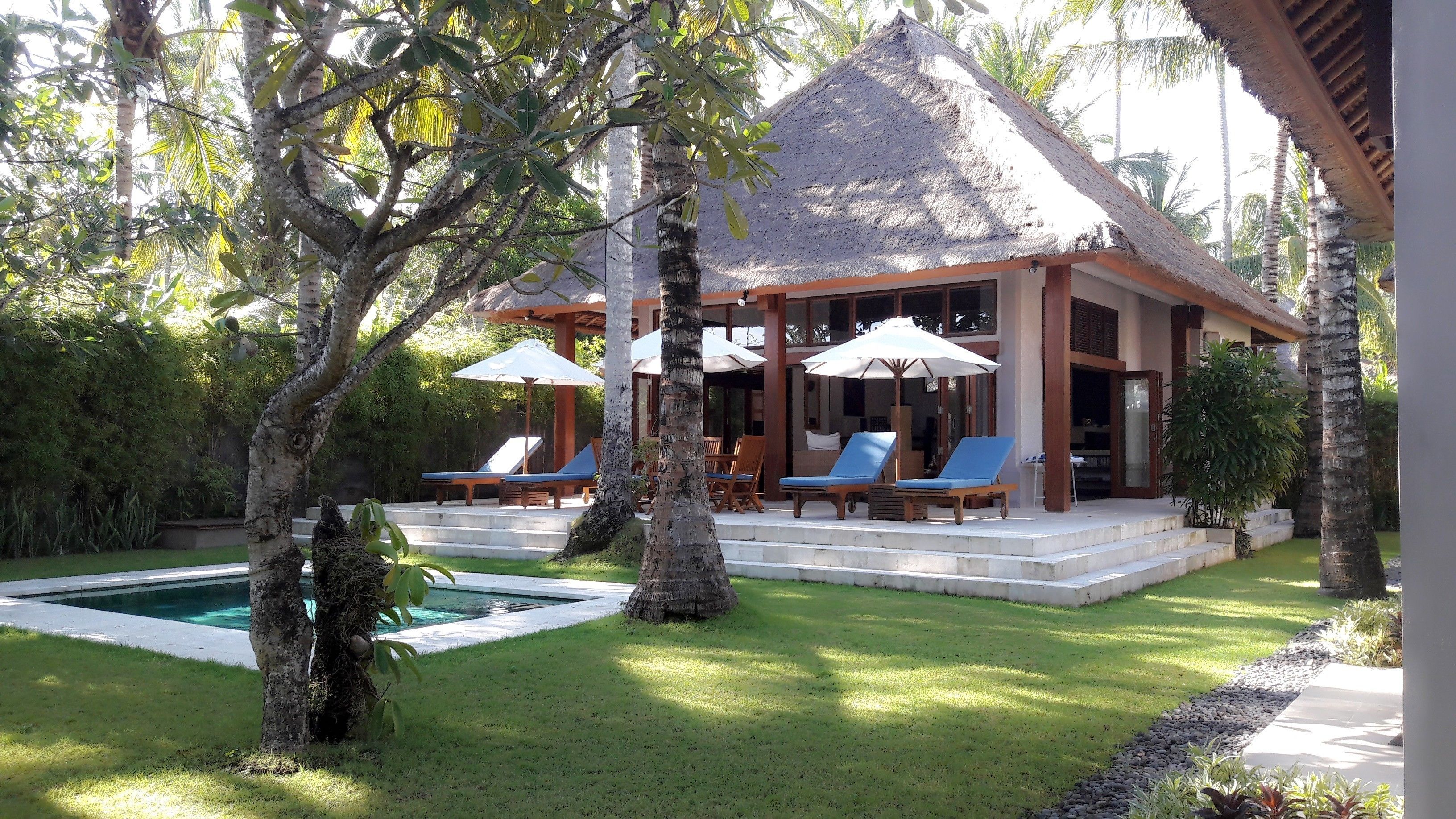 Ein Resort mit Pool, Liegestühlen und einem strohgedeckten Gebäude.