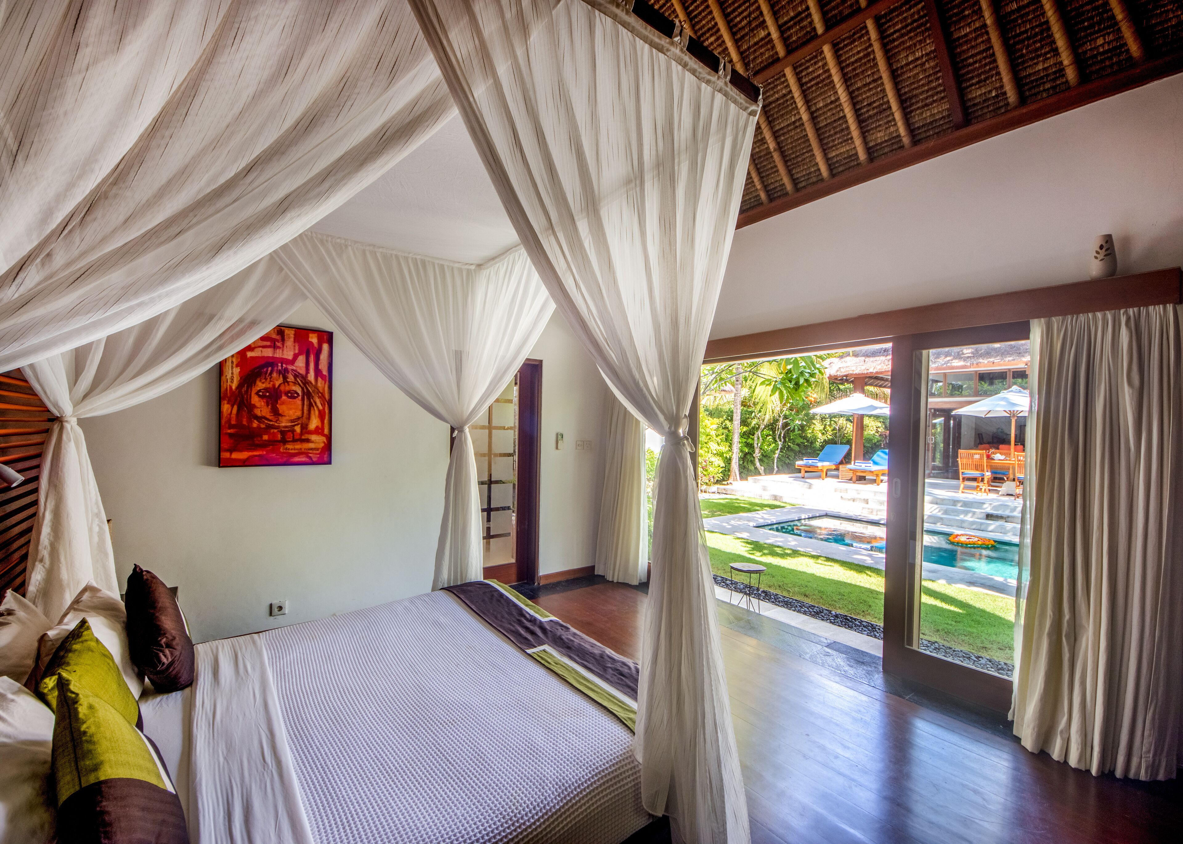 Un dormitorio con cama, un cuadro y vistas a una piscina y zona de estar al aire libre.