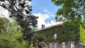 A brick building with ivy-covered walls, a grassy lawn, and white plastic chairs. - Logis Hôtel-Restaurant Le Moulin D'Artres (Artres)