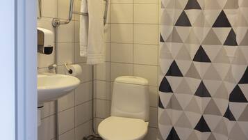 Un baño con lavamanos, inodoro y secamanos blanco.