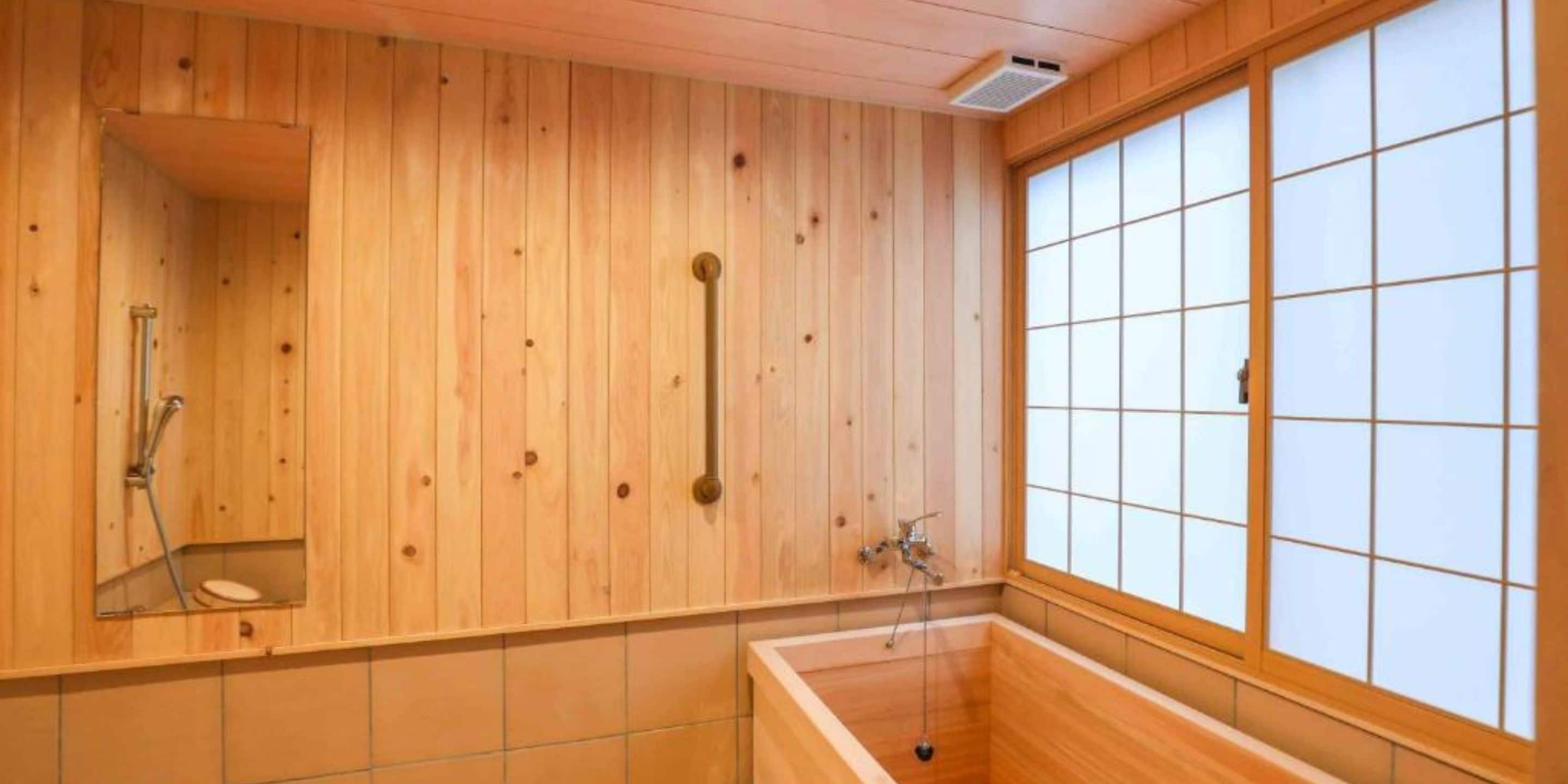 Un interior de madera con una bañera, una ducha y un ventanal con vidrio esmerilado.