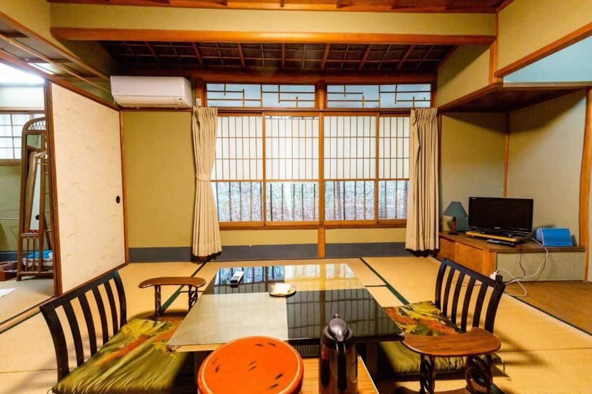A traditional Japanese room with tatami flooring, a low table, and a television on a wooden cabinet.