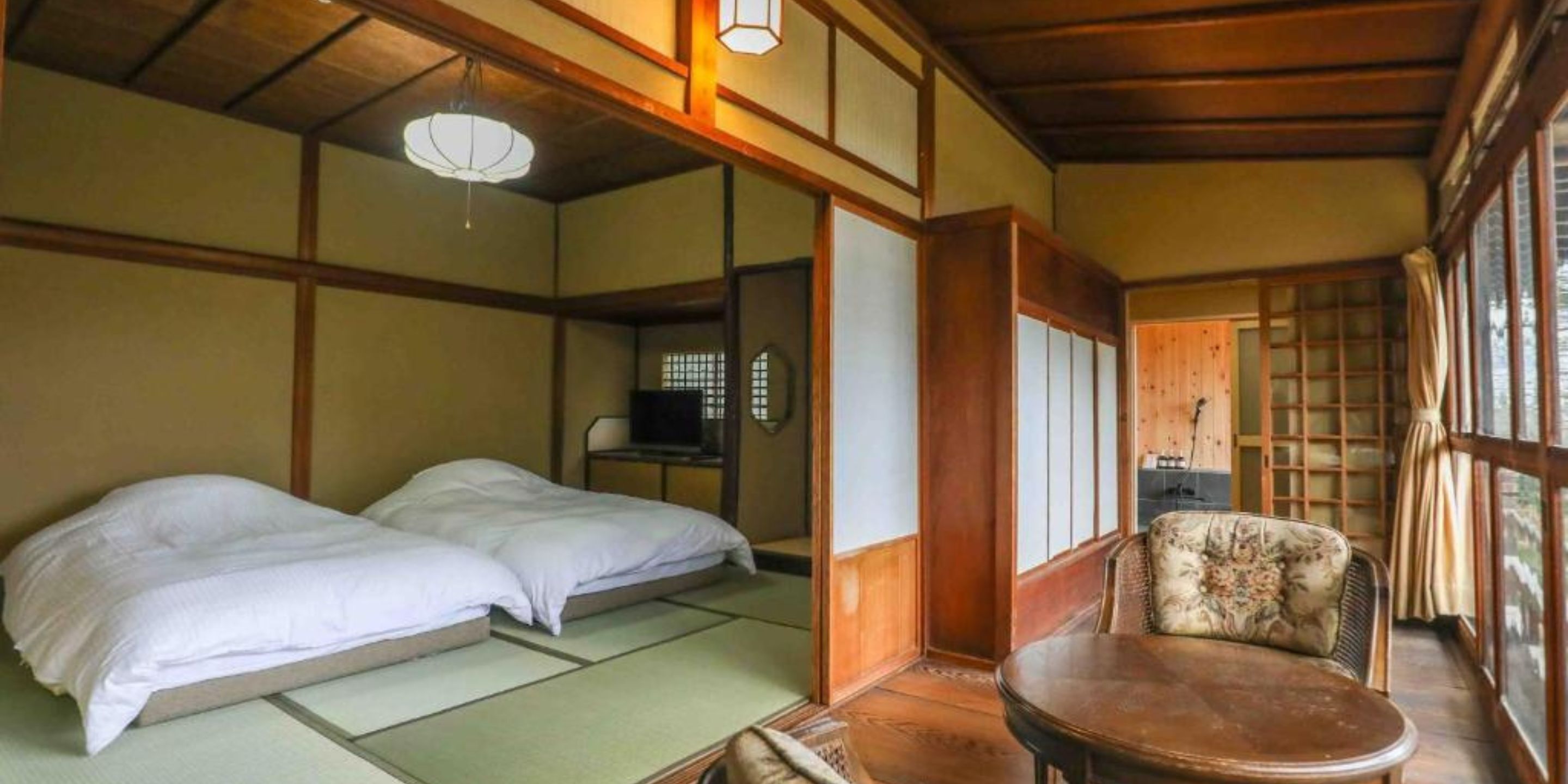 A traditional Japanese room with tatami flooring, a low wooden table, and a futon bed.