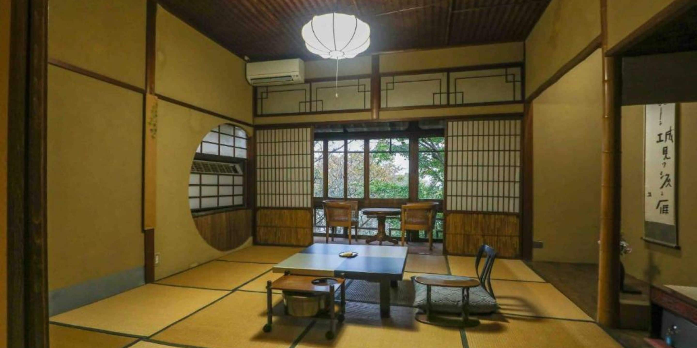 A tatami mat room with a low table, chairs, and a traditional Japanese sliding door.