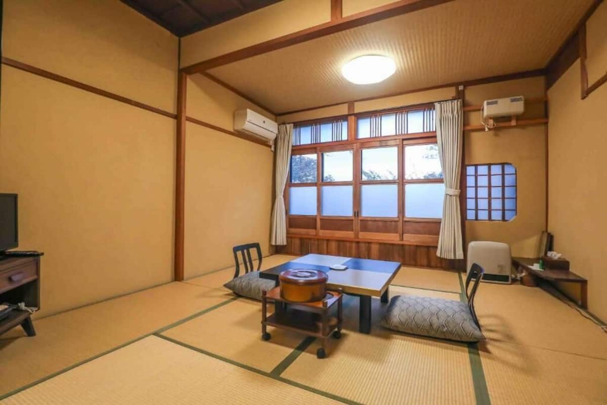 A traditional Japanese room with tatami flooring, a low table, and a television.