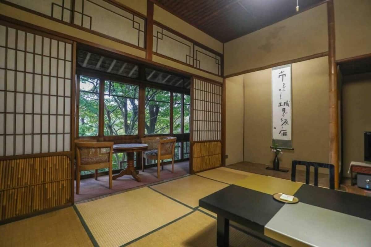 A traditional Japanese room with tatami flooring, a low table, and a sliding door leading to a balcony.