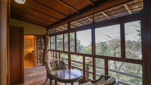 Una habitación con ventanas amplias, vigas de madera en el techo y una mesa redonda con dos sillas.