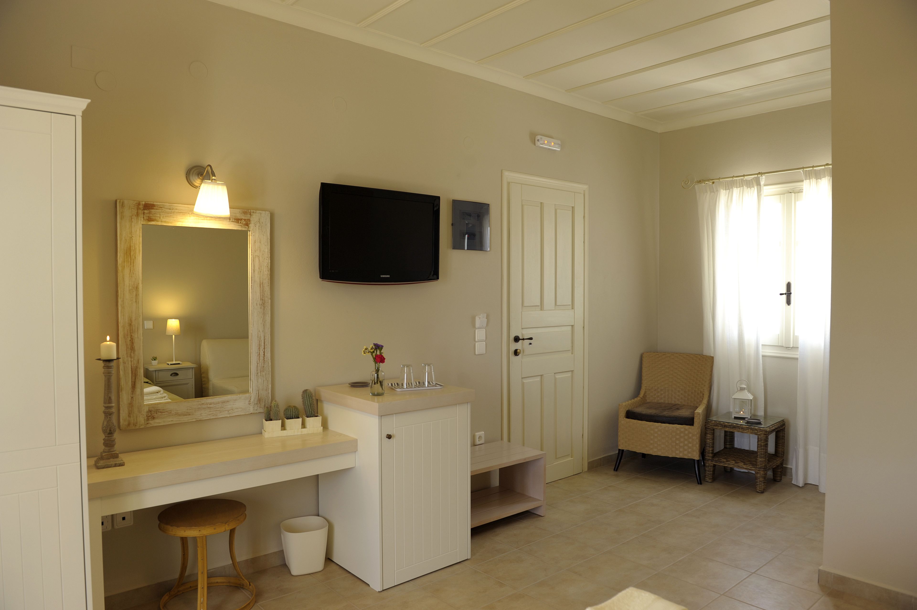A bathroom with a vanity, mirror, television, and a chair.