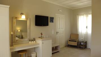 A bathroom with a vanity, mirror, television, and a chair.