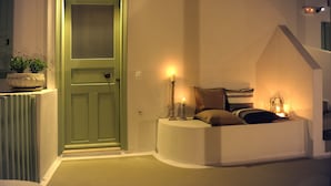 A cozy entryway with a green door, a small seating area with cushions, and a wall-mounted light fixture. - Almyris (Milos)
