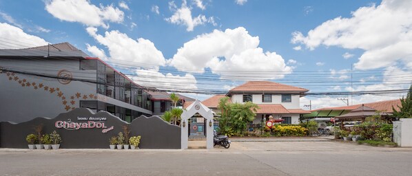 Una entrada con puerta y un letrero que dice "ChayaDOL Resort" y un edificio con techo de tejas rojas.