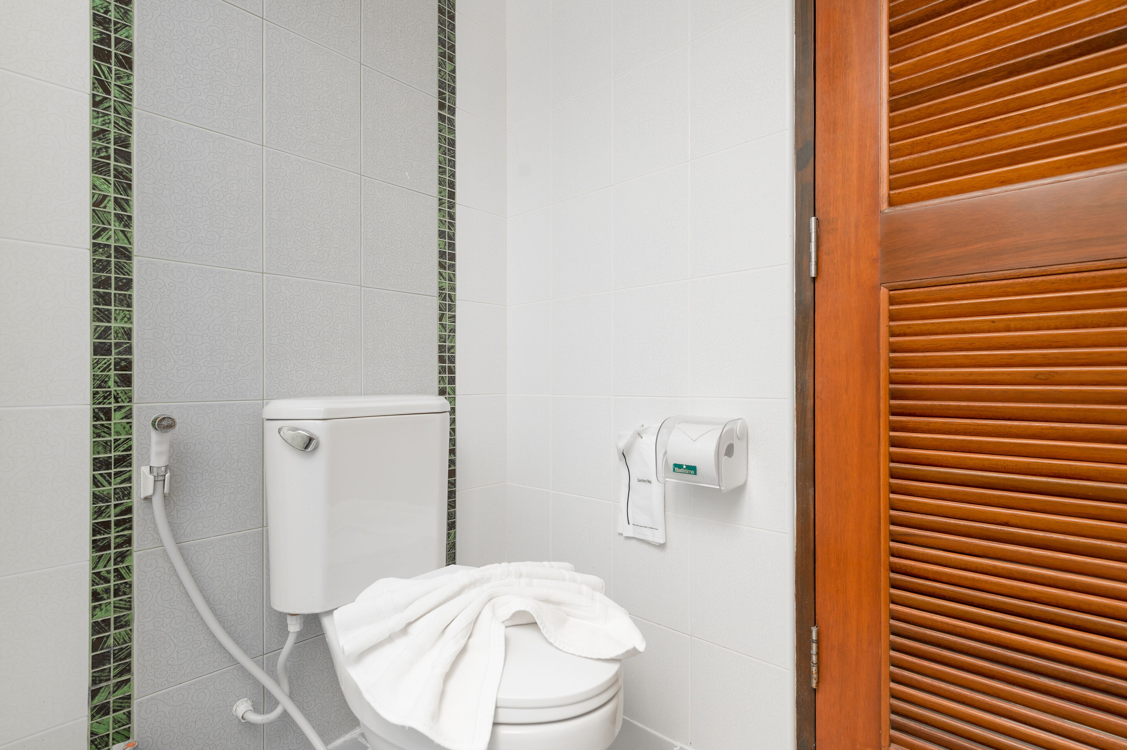 A bathroom with a toilet, a hand dryer, and a paper towel dispenser.