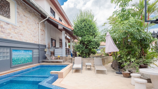 Une piscine avec des marches carrelées, des chaises longues et des plantes en pot.