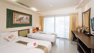 A hotel room with two beds, a desk with a TV, a chair, a teddy bear on one bed, and a painting on the wall.