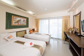 A hotel room with two beds, a desk with a TV, a chair, a teddy bear on one bed, and a painting on the wall. - Chayadol Resort (Chiang Rai)