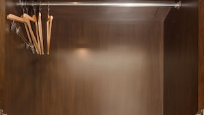 Un dressing avec des portemanteaux en bois, un meuble à chaussures et un coffre-fort encastré.