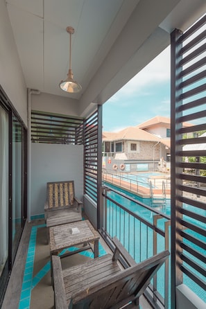 A balcony with a pool, wooden furniture, and a hanging light fixture.