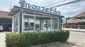 A small, glass-walled building with a sign indicating it is a 24-hour service center.