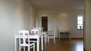 A dining area with white furniture and a patterned wall.