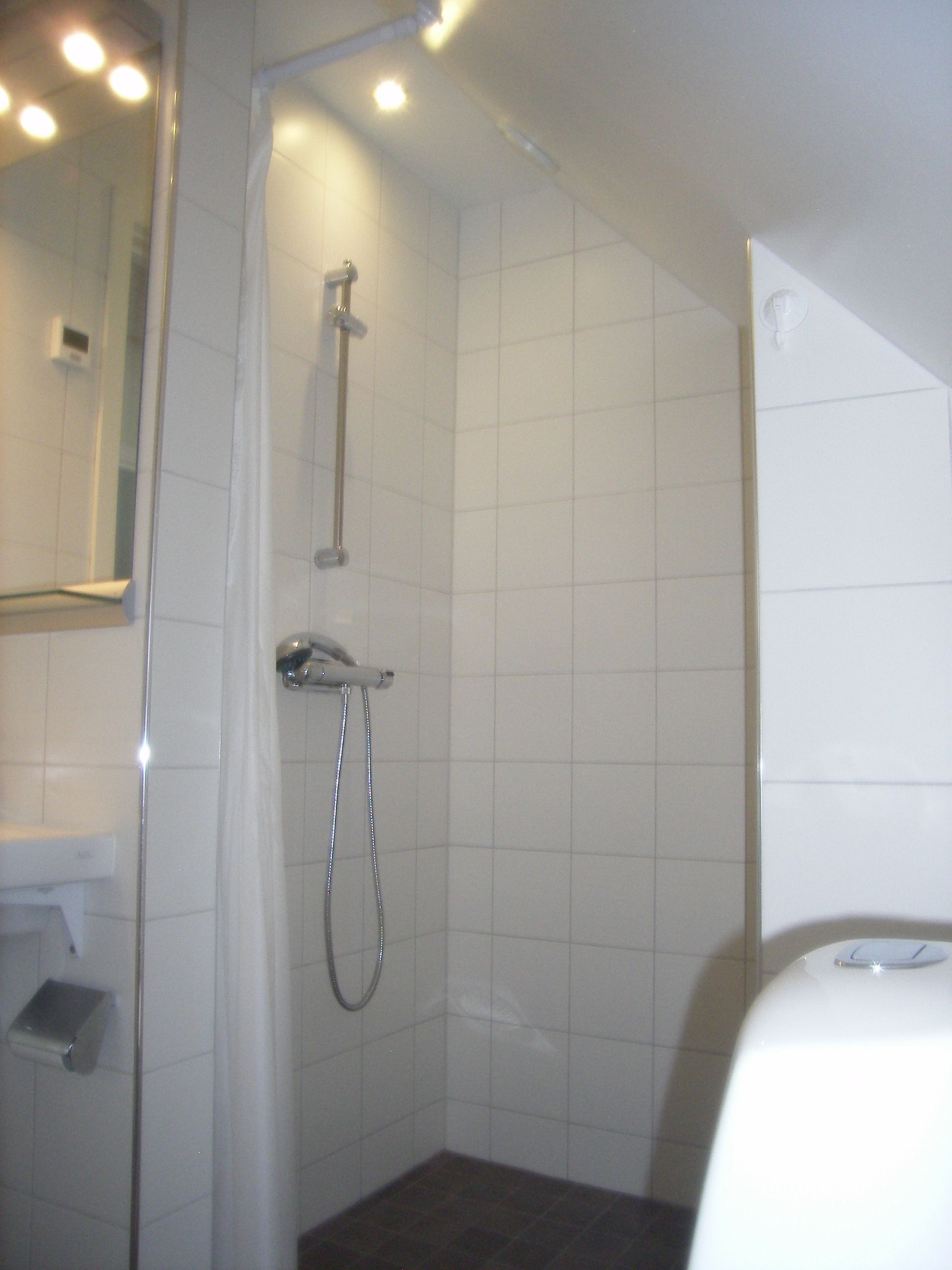 A small, tiled shower area with a handheld showerhead and a wall-mounted faucet.