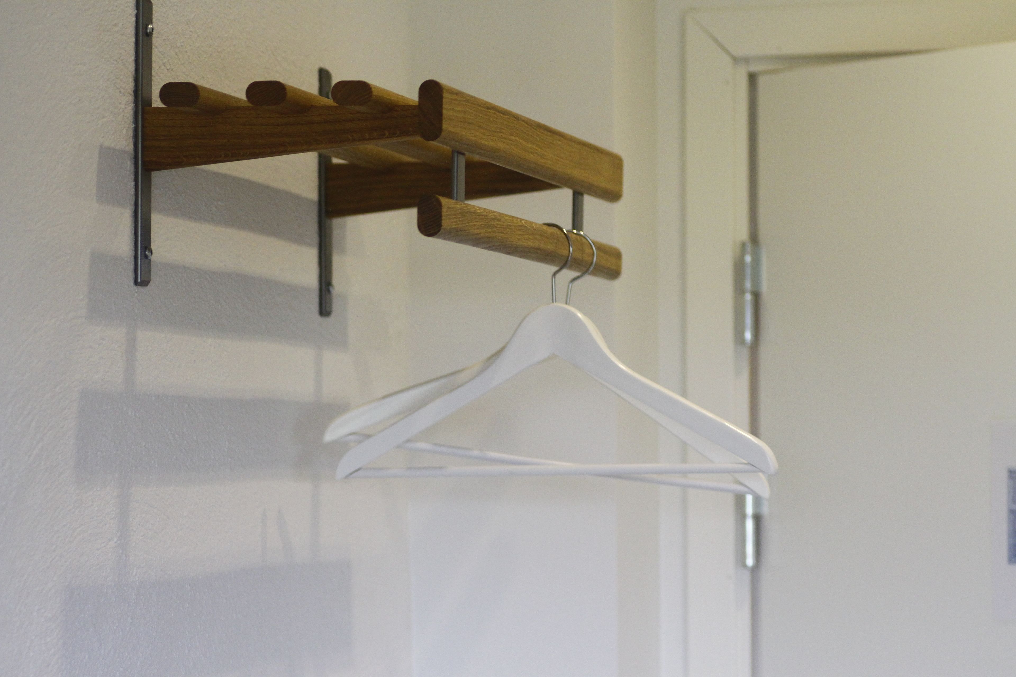 Un perchero de madera con varios ganchos y un colgador blanco.