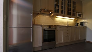 A modern kitchen with stainless steel appliances, beige cabinetry, and a tiled backsplash.