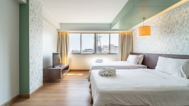 A hotel room with two beds, a desk, a TV, and a large window with curtains. - Veronica Residence (Bangkok)