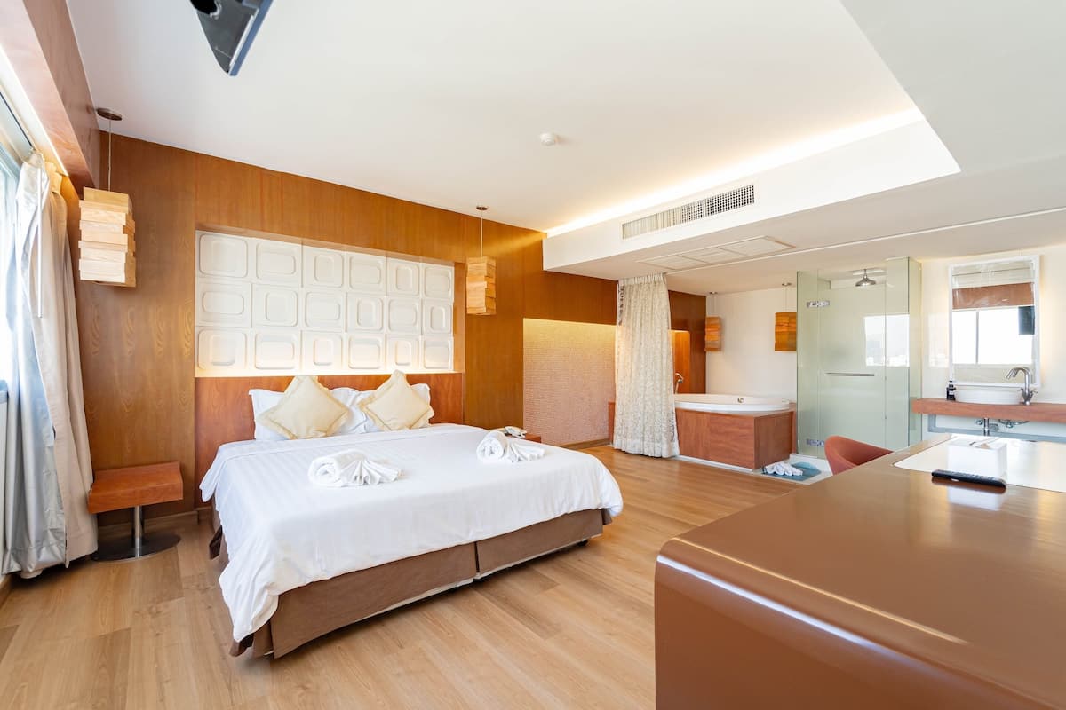 A hotel room with a large bed, a desk, a bathroom, and a view of the city.