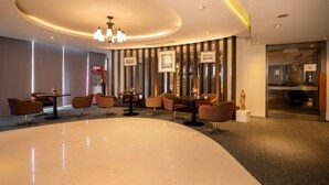 A modern lobby with a curved seating area, a central chandelier, and framed artwork on the walls. - Veronica Residence (Bangkok)