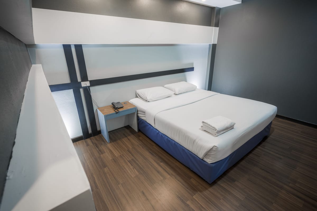 A modern hotel room with a bed, bedside table, and a power outlet.