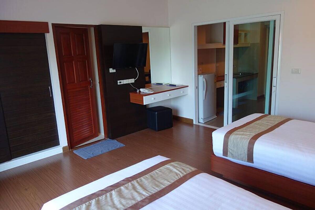 A hotel room with a bed, a desk with a computer, a television, and a wardrobe.
