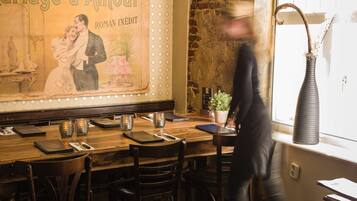 Interior de restaurante con una mesa de madera, sillas, un florero y un cartel en la pared.