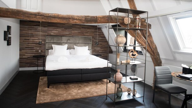 Une chambre moderne avec un grand lit, une tête de lit en bois, une étagère en verre et un bureau avec une chaise.