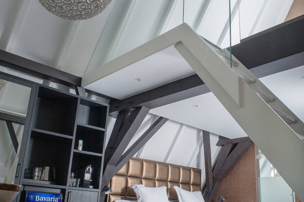 Een moderne hotelkamer met een groot bed, een minibar en een balkon met glazen wanden.