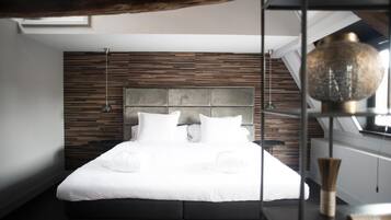Un dormitorio moderno con cama, panel de madera en la pared y una lámpara colgante.