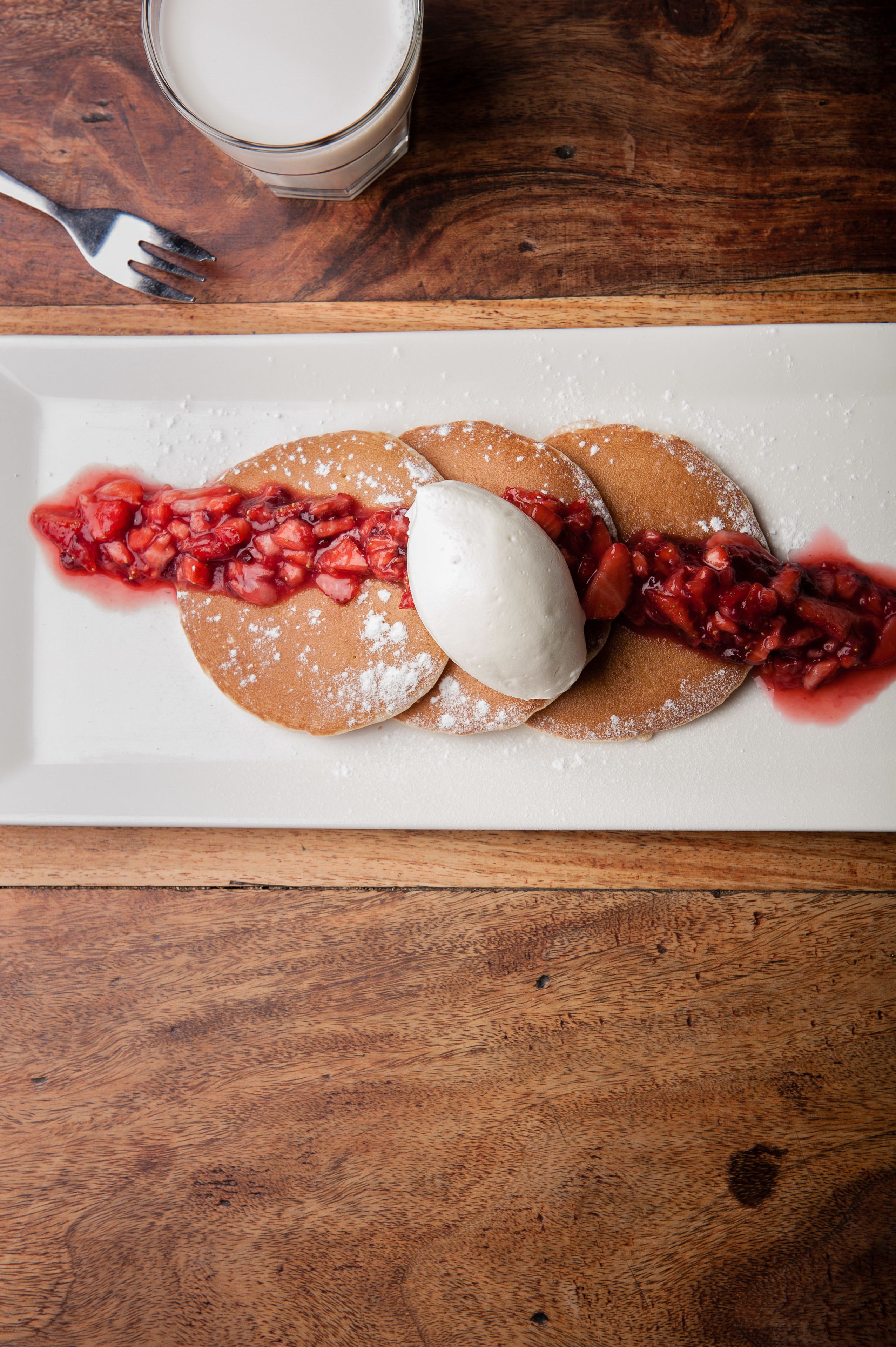A plate with pancakes, a scoop of ice cream, and a berry compote.