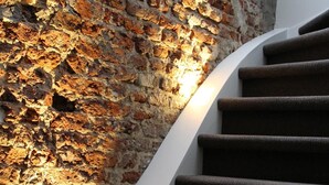 Un escalier, avec un mur en briques à texture sur un côté et un mur blanc de l’autre.
