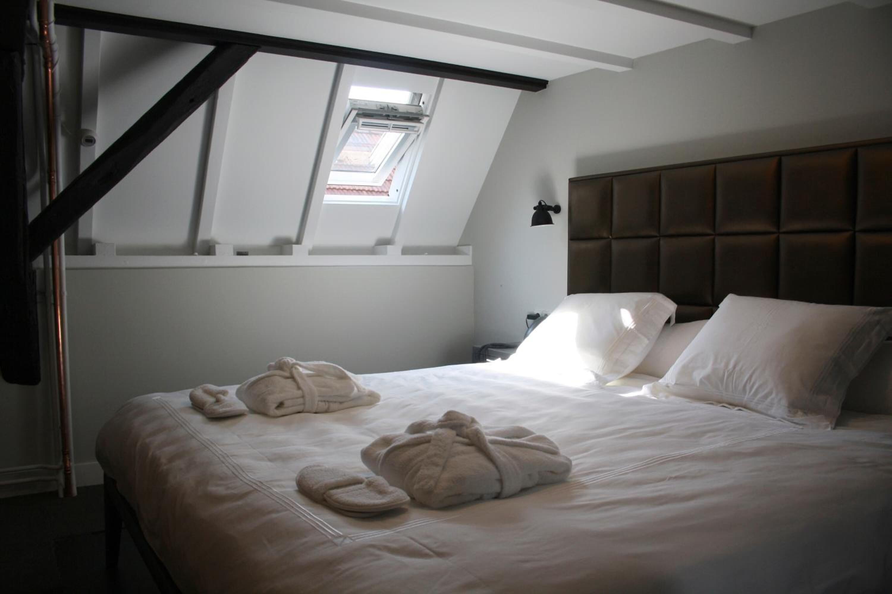 Une chambre d’hôtel avec un lit, une tête de lit et une lucarne.