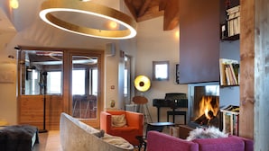 A modern living room with a fireplace, wooden beams, and a cozy seating area. - Hôtel Pashmina (Les Belleville)