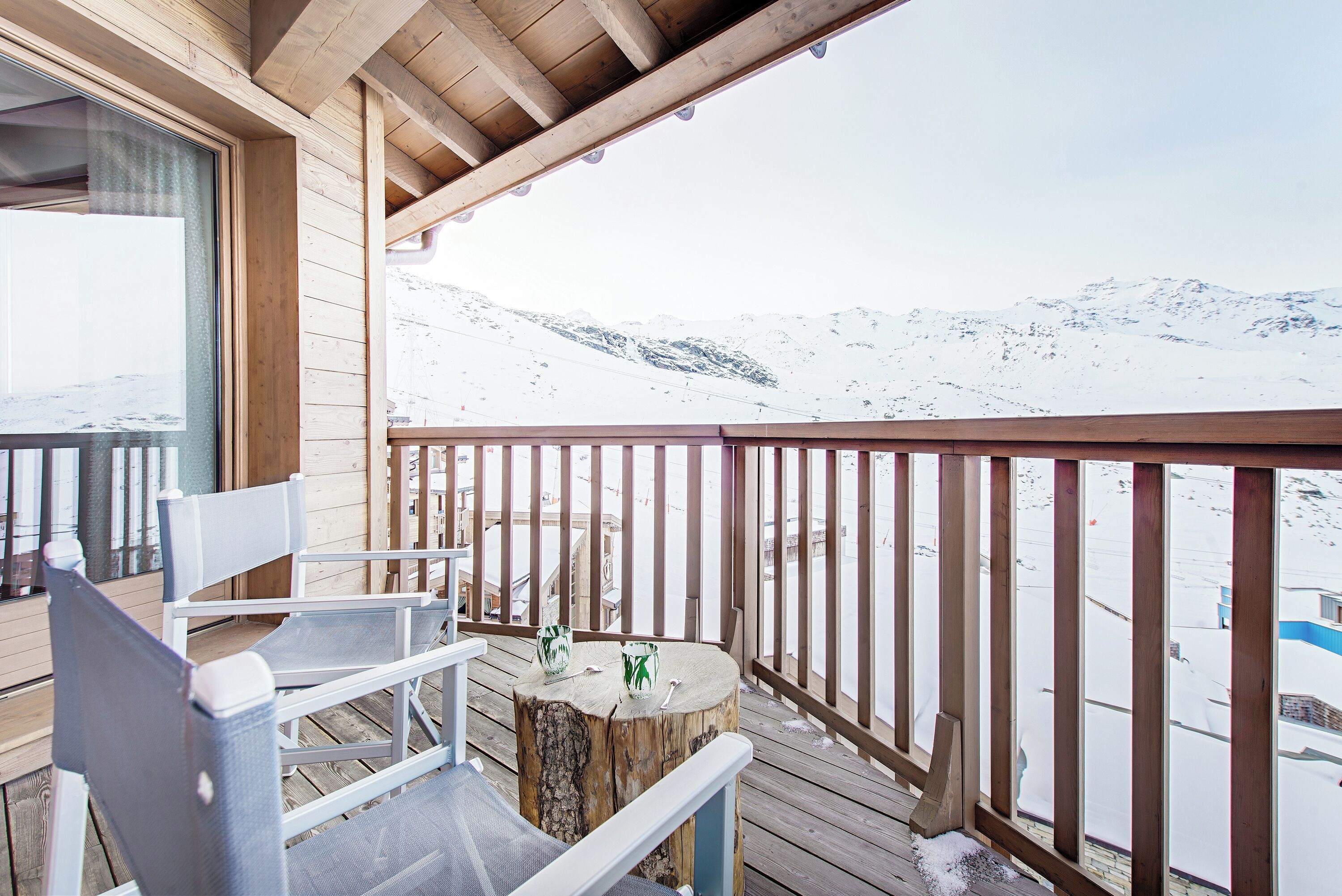 A wooden deck with a view of snow-covered mountains.