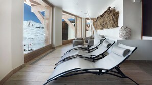 A modern lounge area with large windows offering a view of a snowy mountain. - Hôtel Pashmina (Les Belleville)