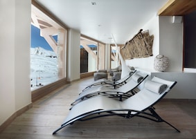 A modern lounge area with large windows offering a view of a snowy mountain.