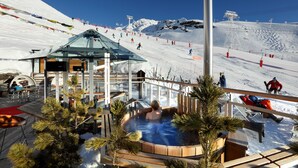 A hot tub area with a view of a ski slope and a mountain in the background. - Hôtel Pashmina (Les Belleville)